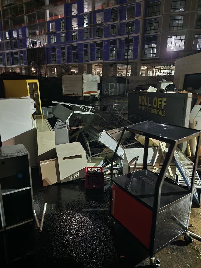 Office desks, filing cabinets and chairs stacked beside a roll-off container during a commercial cleanout