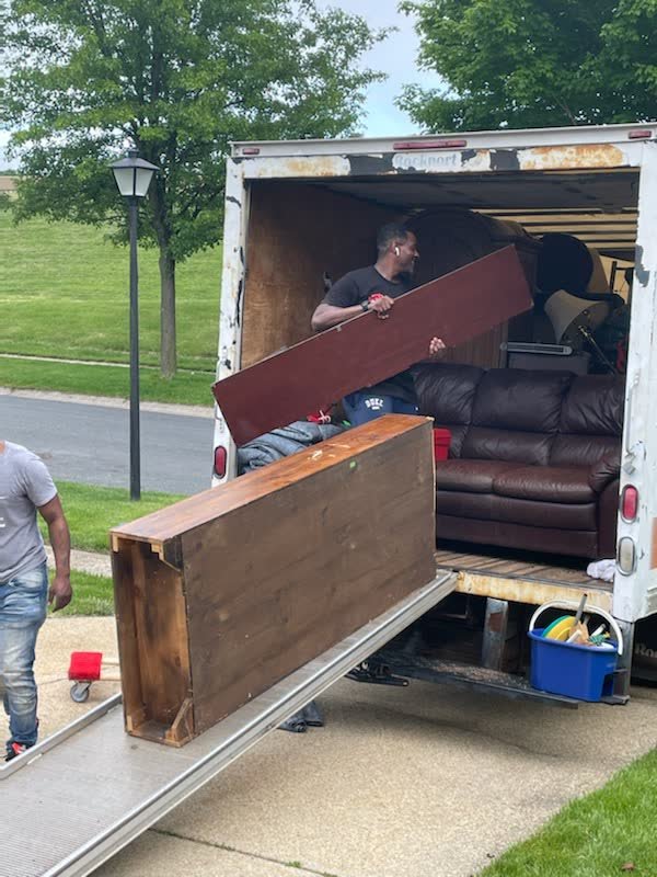 Crew member guiding a wooden cabinet up the ramp into a Rich Brothers box truck
