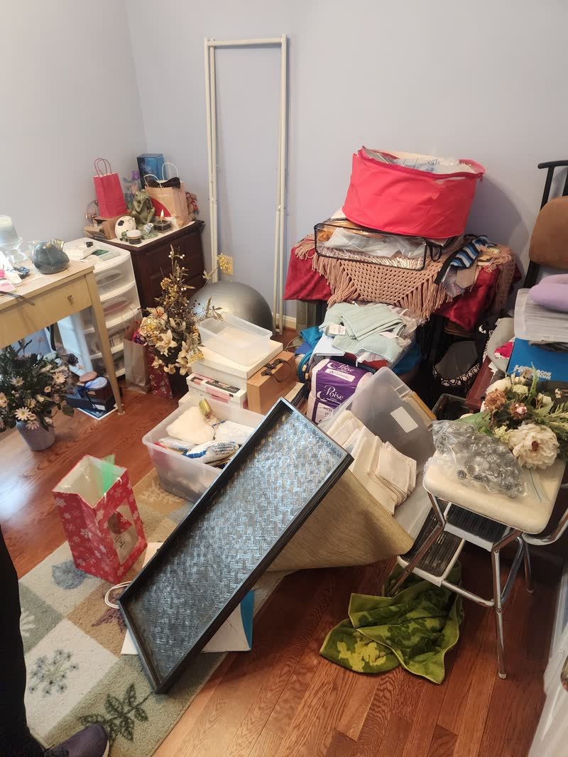 Room filled with household clutter, boxes, furniture and decorations before a hoarding cleanout