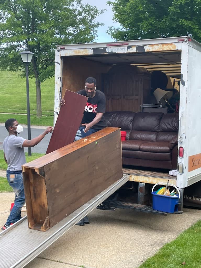 Rich Brothers crew loading a wooden dresser and leather sofa into a box truck during a furniture removal job